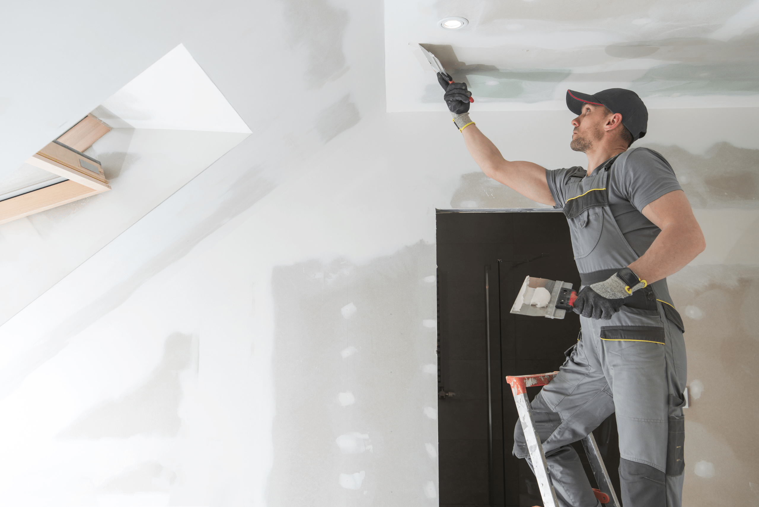 A person using drywall compound to smooth out drywall.
