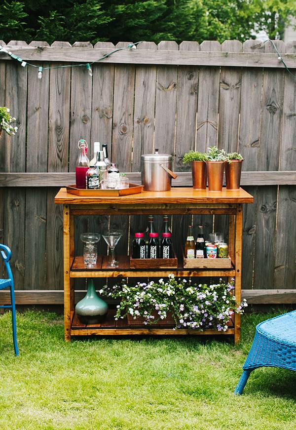 An outdoor wooden bar filled with drinking essentials.