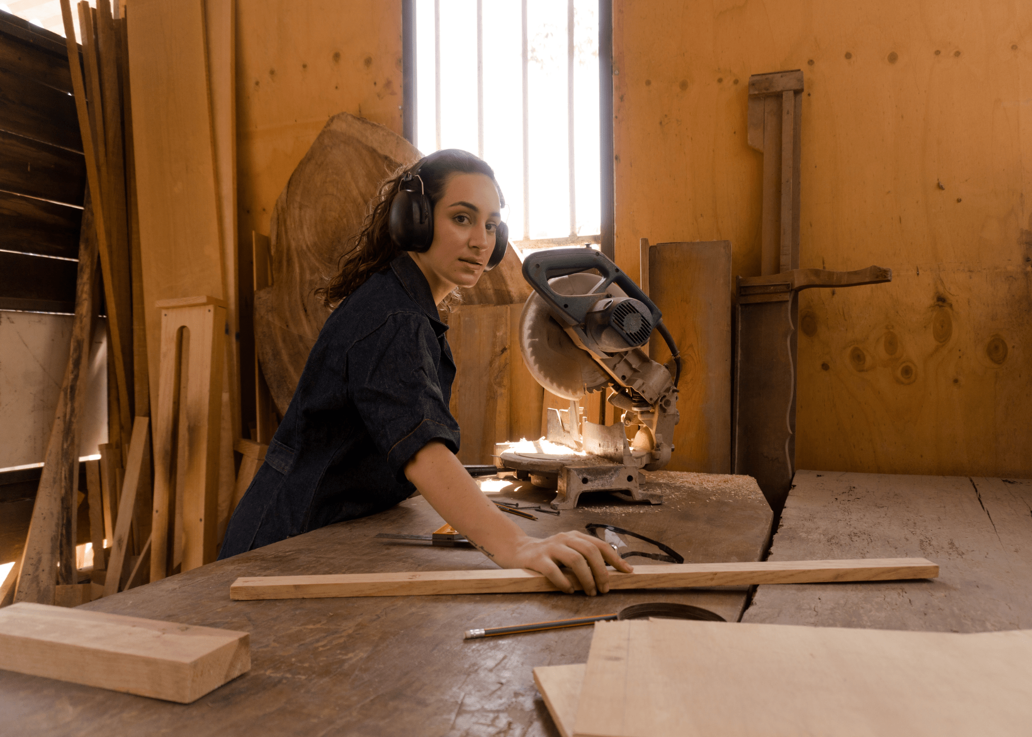 woman reaching for wood working on a miter saw