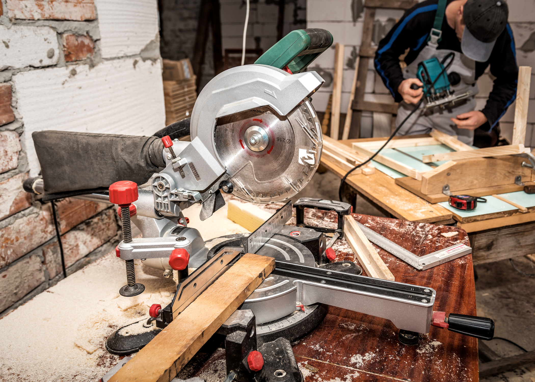 miter saw on workbench with man working in the background