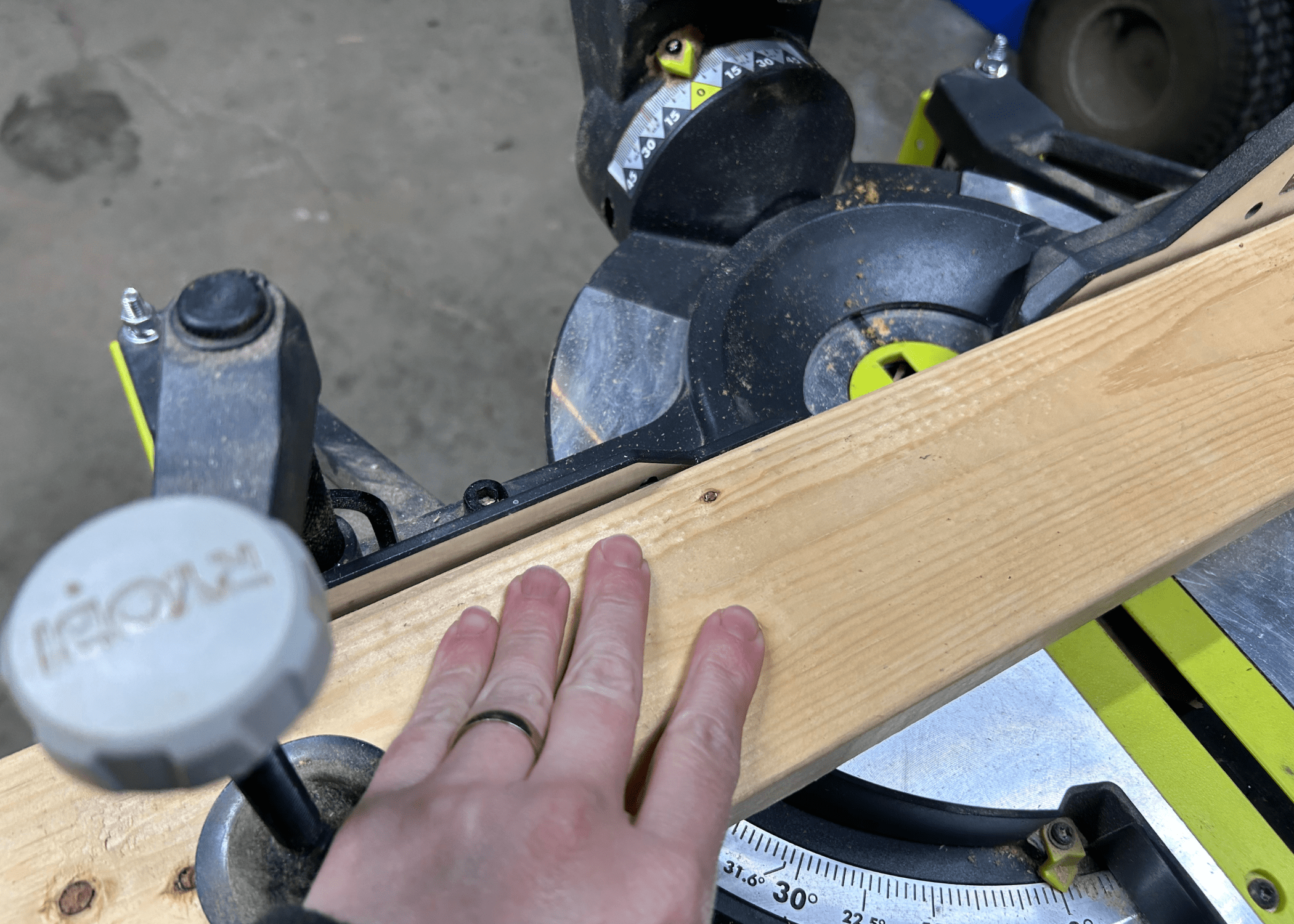 pushing wood against the fence of a miter saw