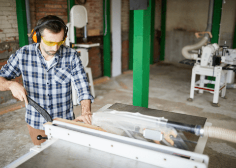 carpenter using a table saw with safety glasses