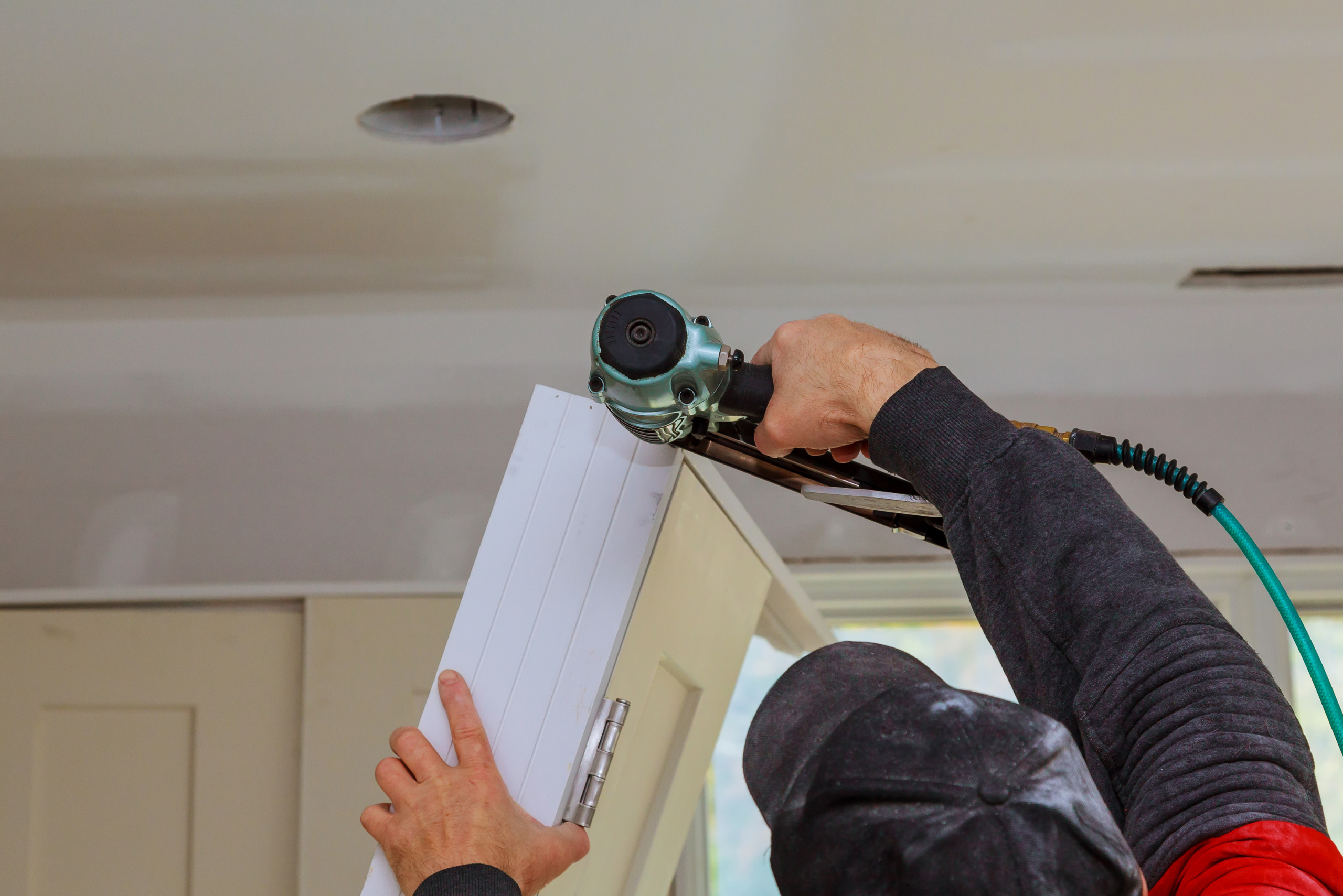 Brad nailer being used by a man to secure door frame.