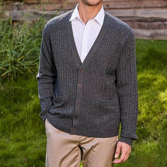 A man wearing a cardigan sweater outdoors.