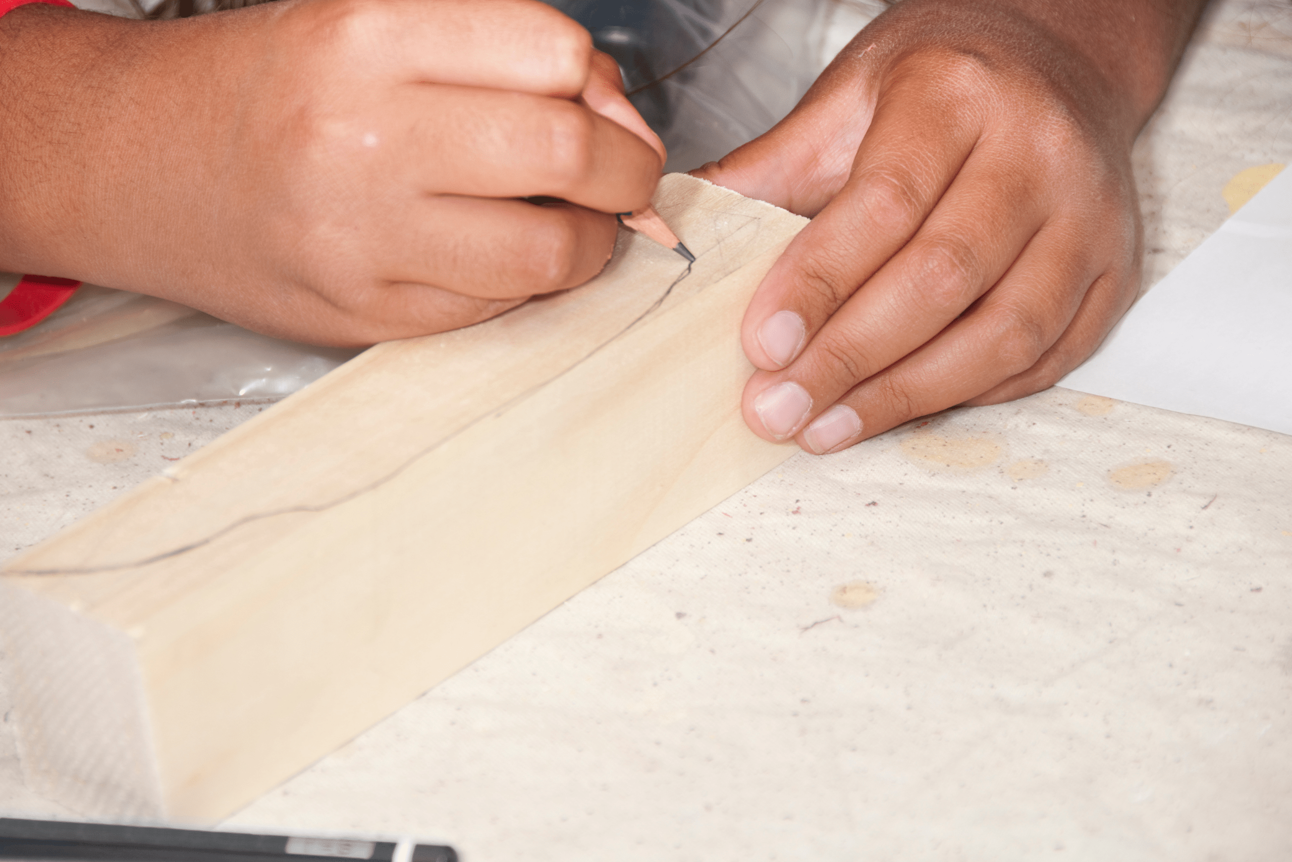 Closeup of someone's hands drawing a line for pinewood derby car.