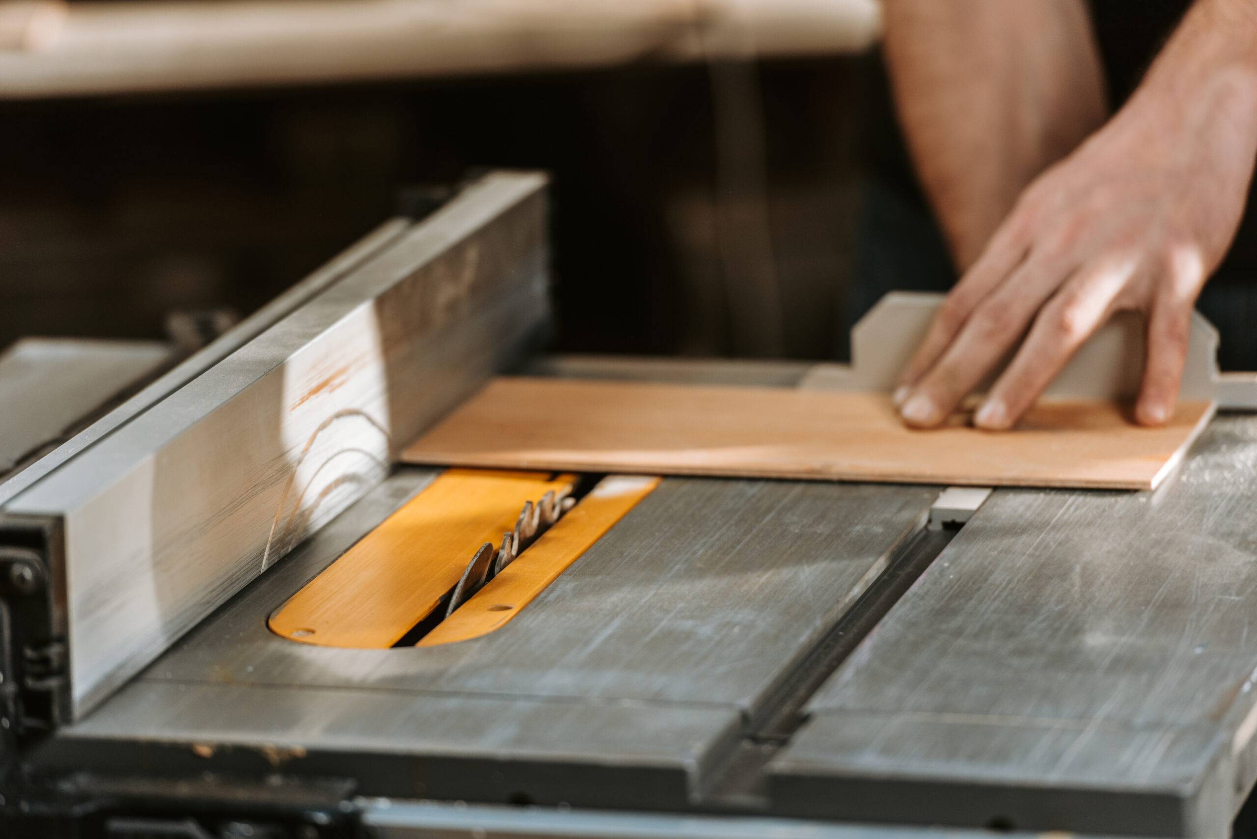 cropped view of carpenter holding wooden plank near circular saw