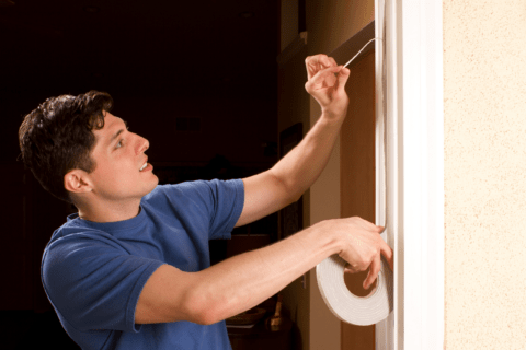 Person applying weather stripping to a door.