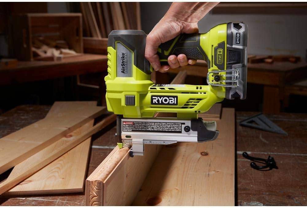 Green pin nailer being used on wood.