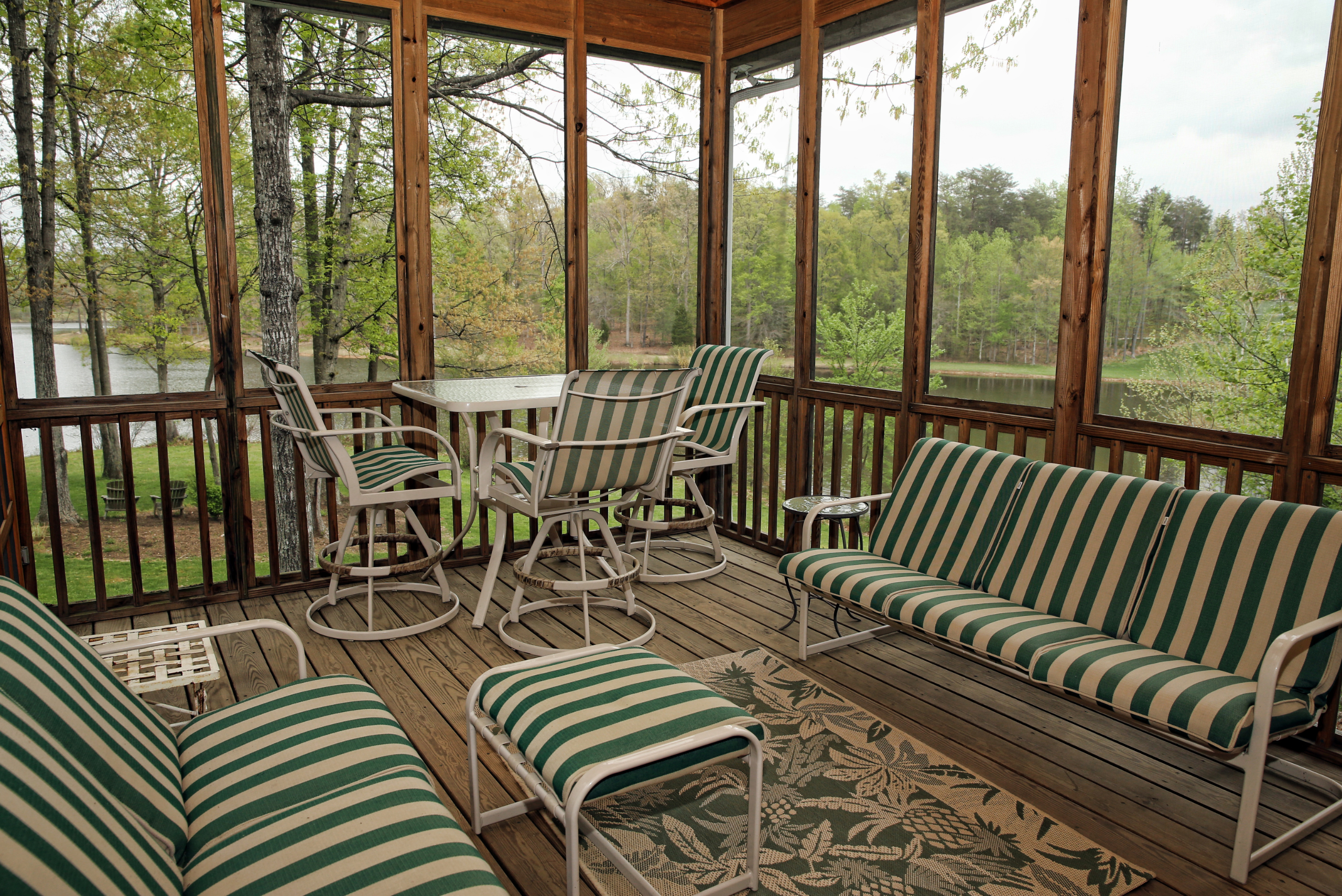 Striped furniture in a screened-in porch with wood framing.
