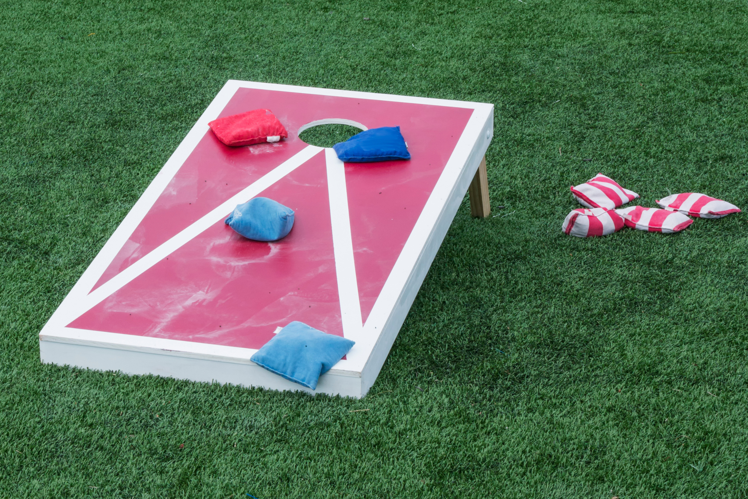 Red corn hole board with white lines.