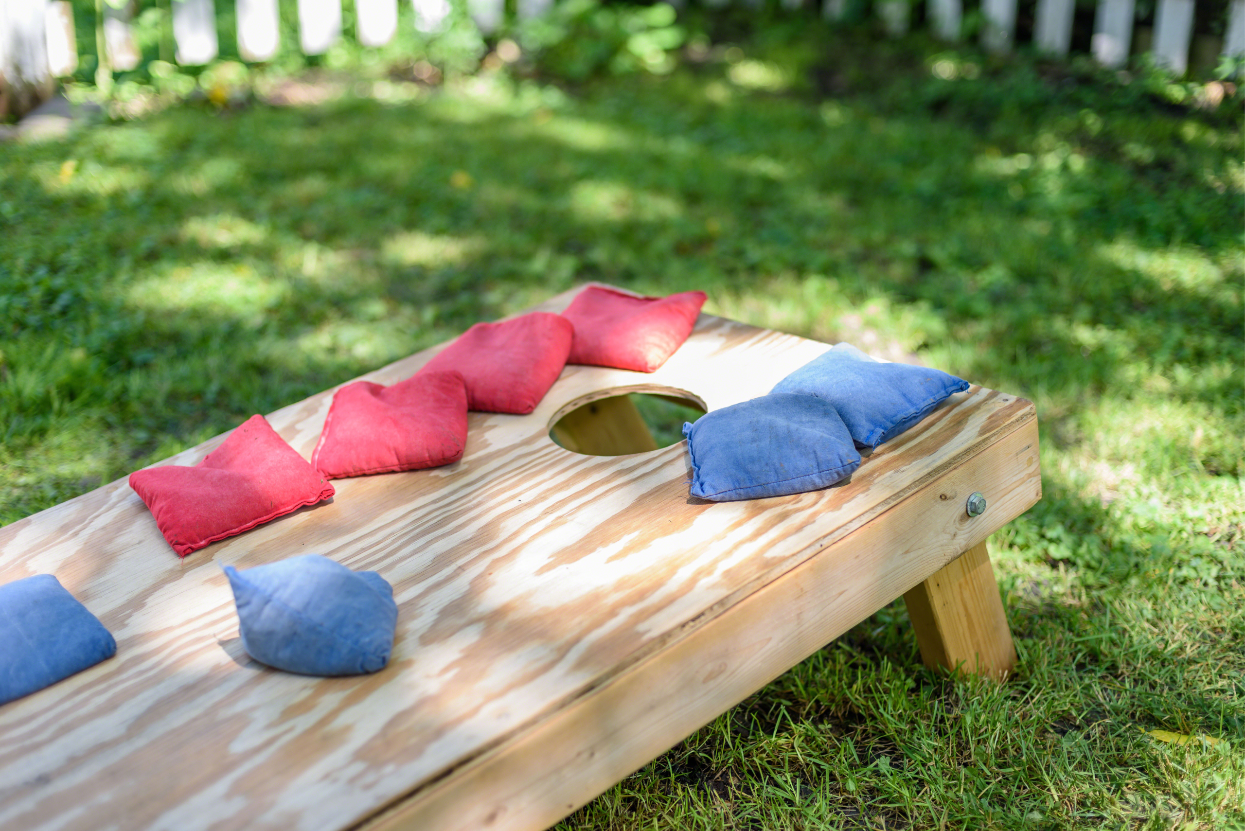 Red and blue bean bags on top of a wooden corn hole board.