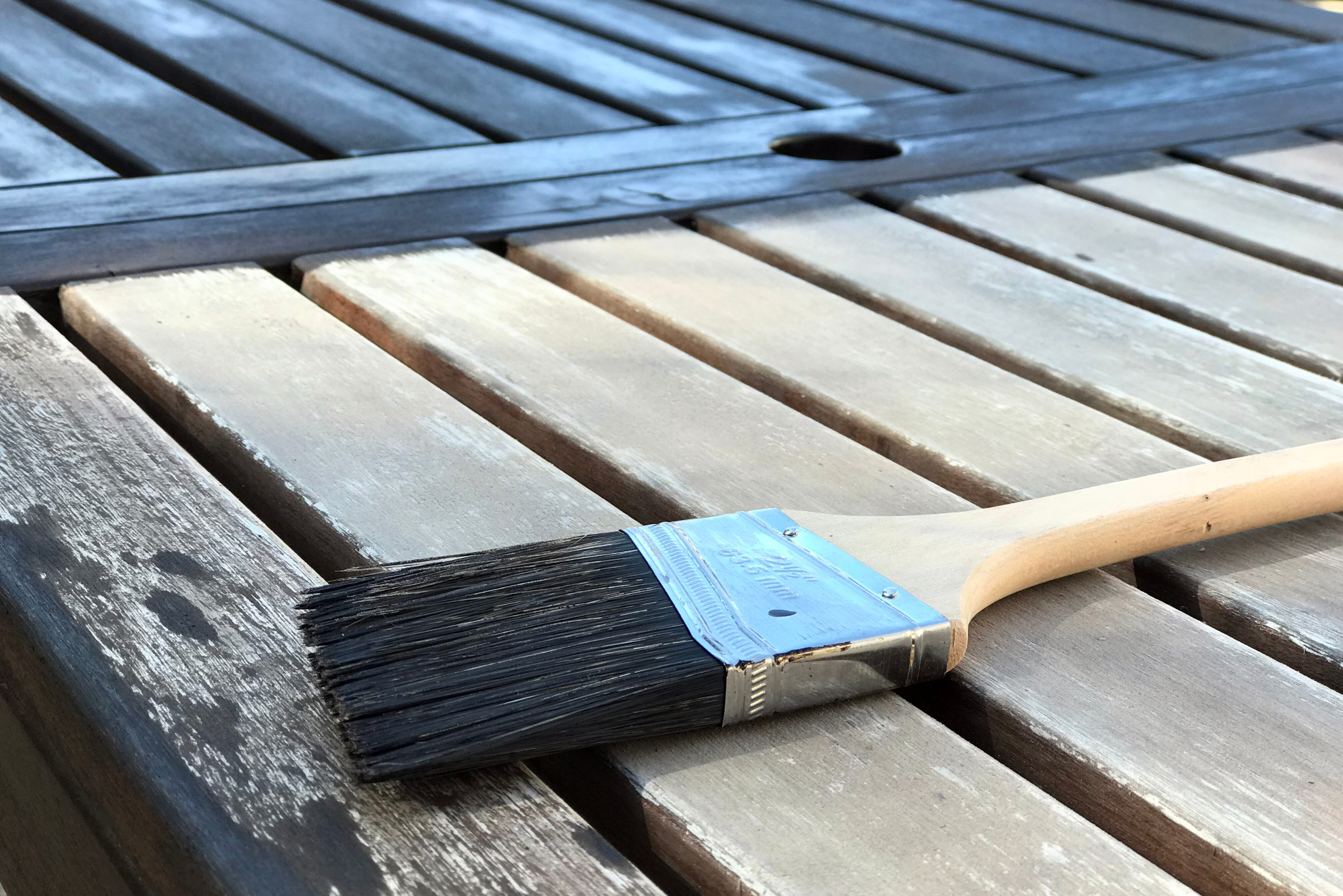 A stained DIY wooden outdoor furniture mid stain with brush on top.