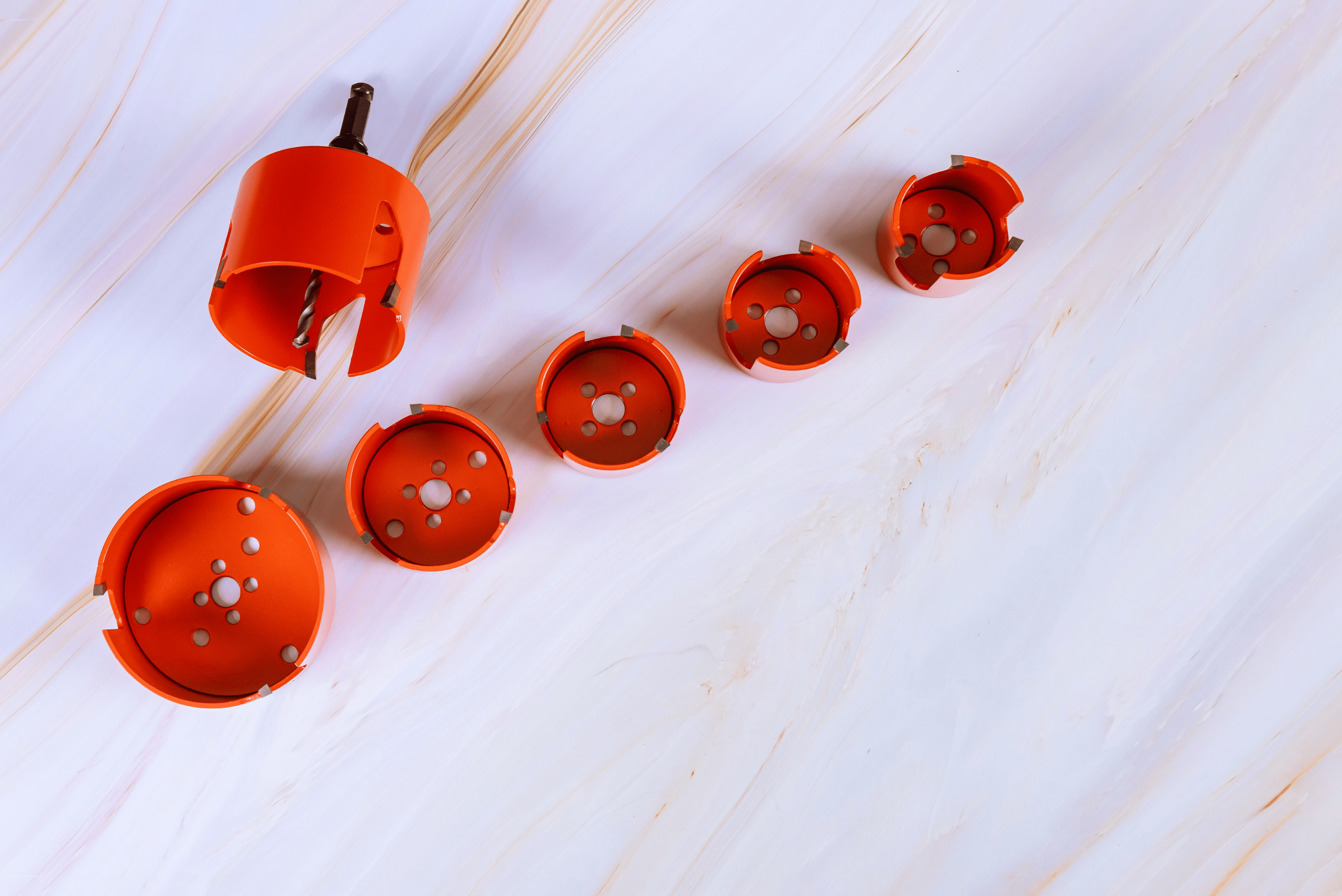 An assortment of red hole saw bits for a drill.