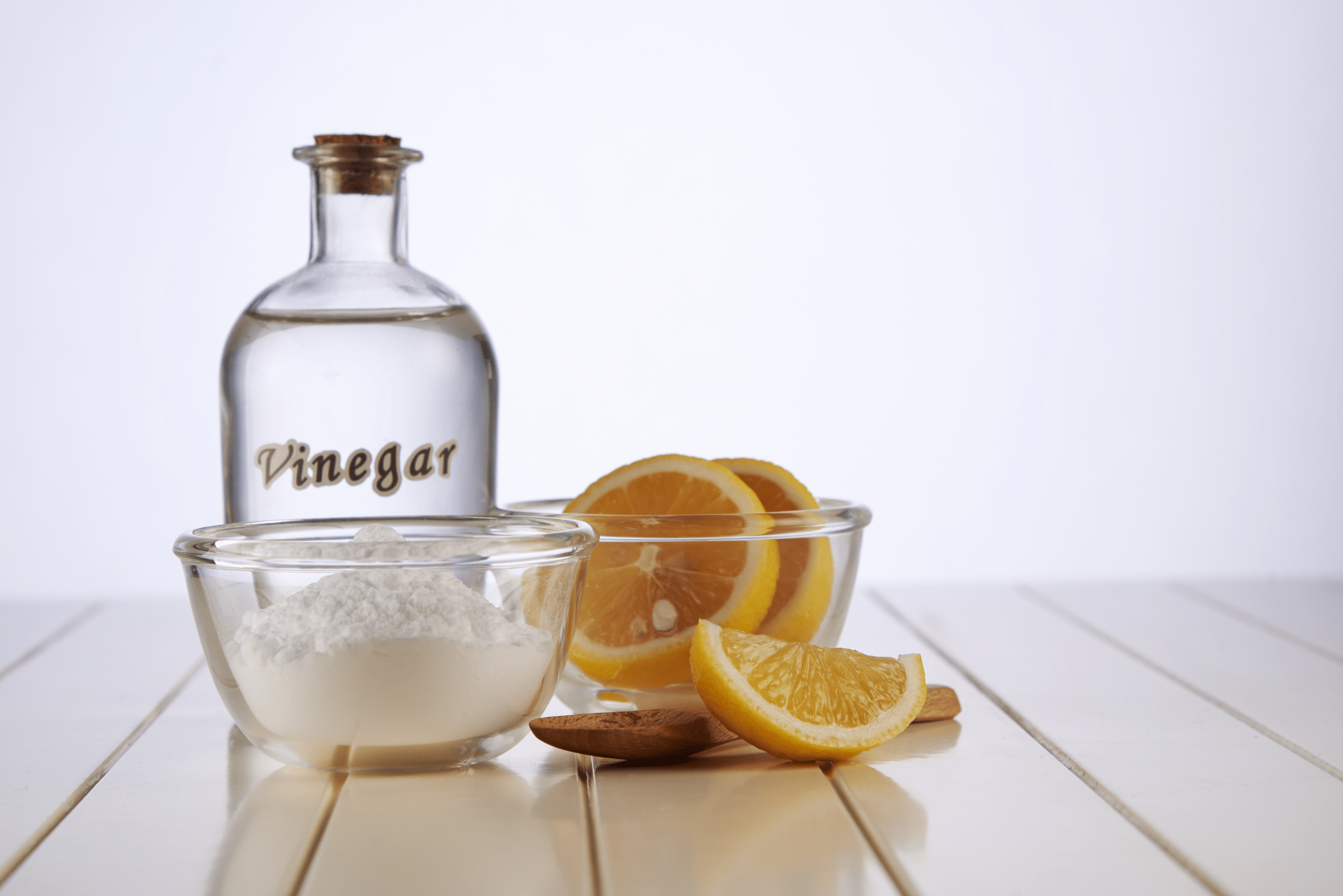 A bottle of vinegar and a bowl of lemon slices.