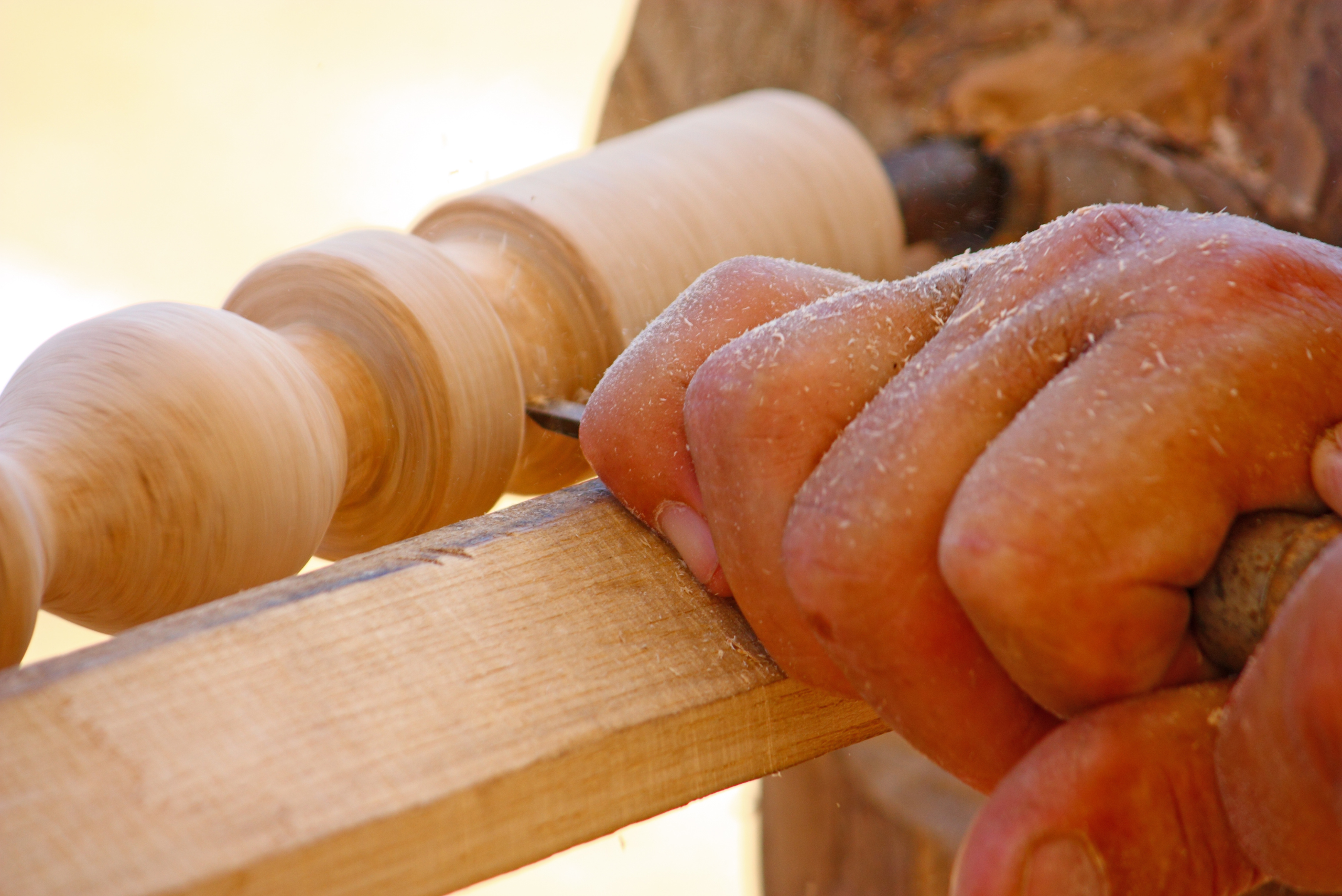 A closeup of someone's hand holding a chisel to turn a piece of wood into a stunning piece.