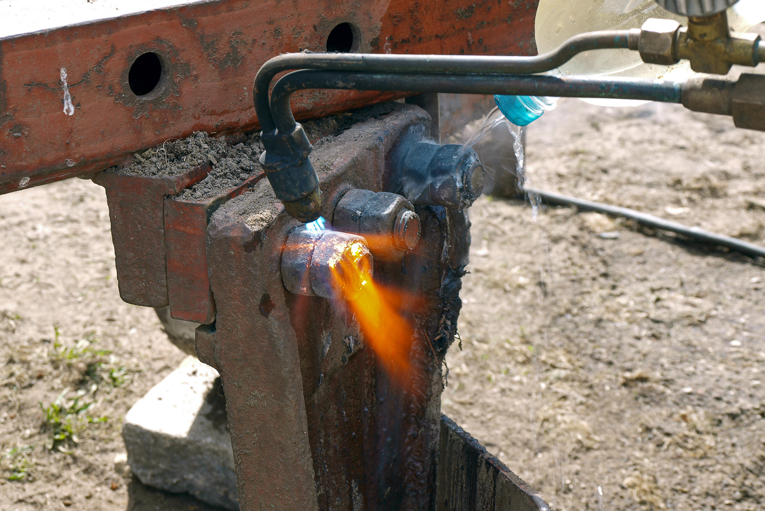 Rusty nuts being heated by torch.