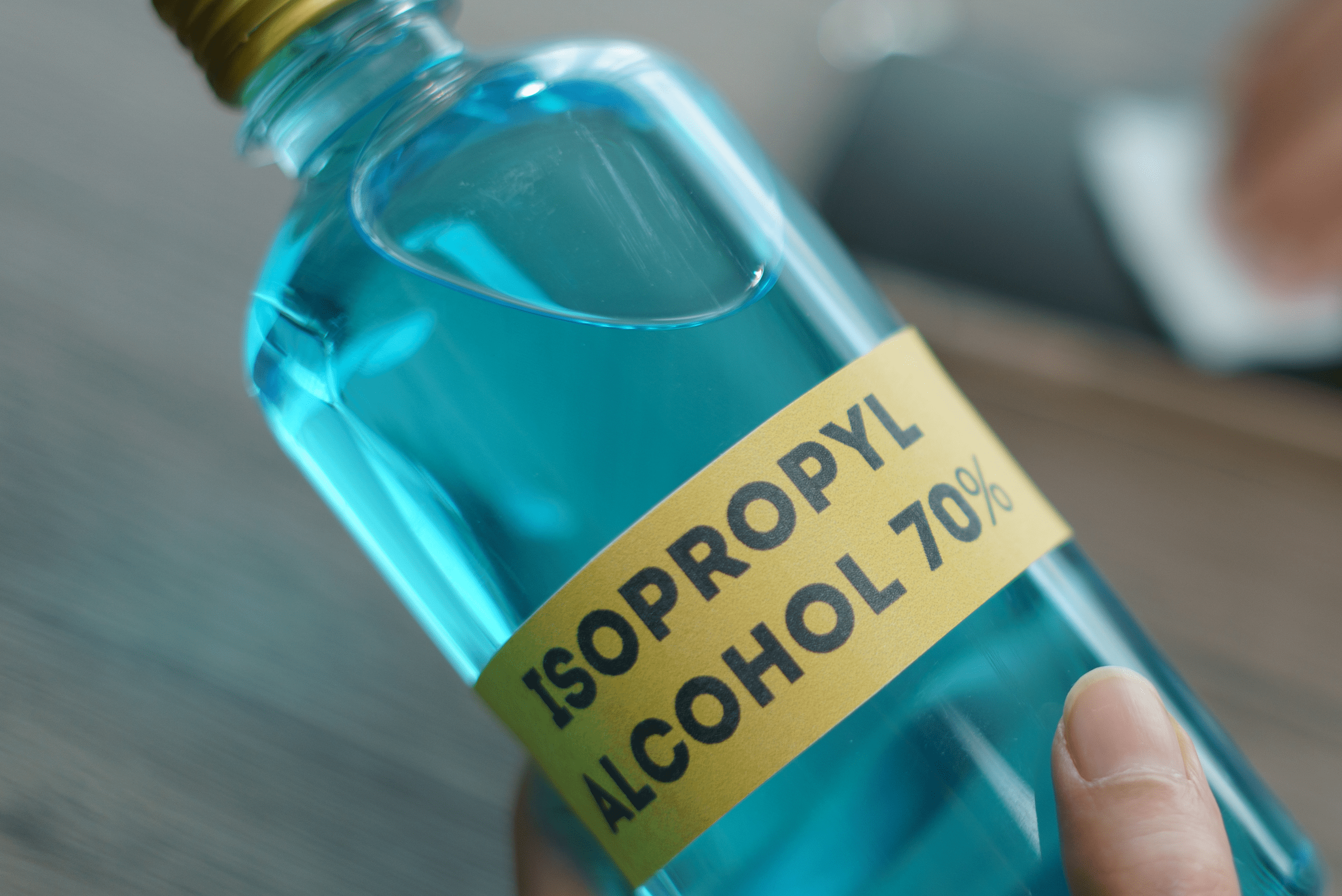 Isopropyl alcohol bottle with blue liquid inside of it.
