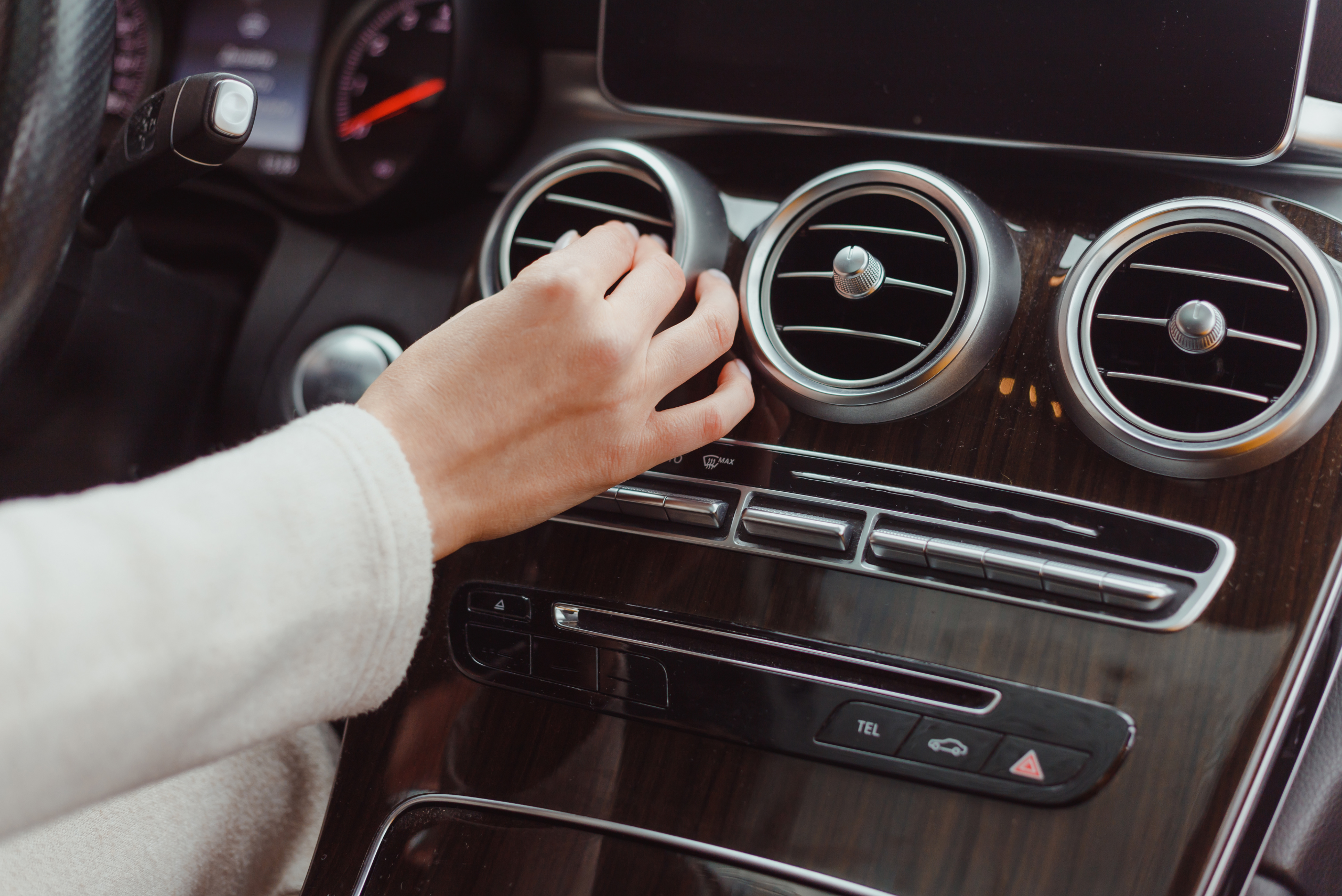 A person adjusting AC vents inside a car interior.