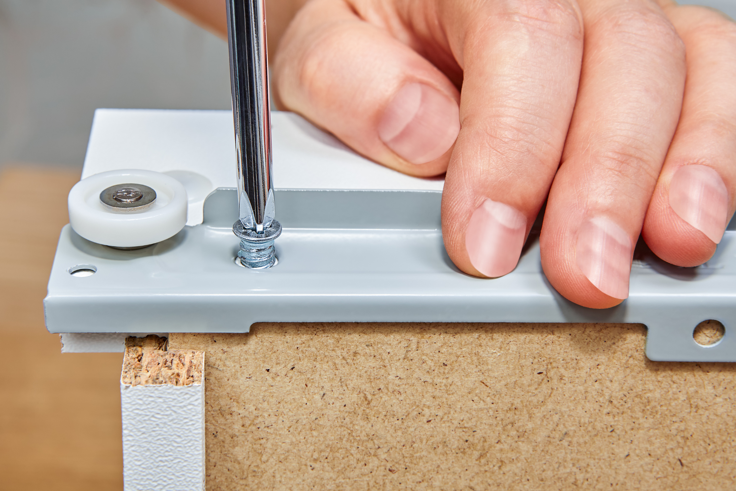 Screwing on a slide onto wooden drawer.