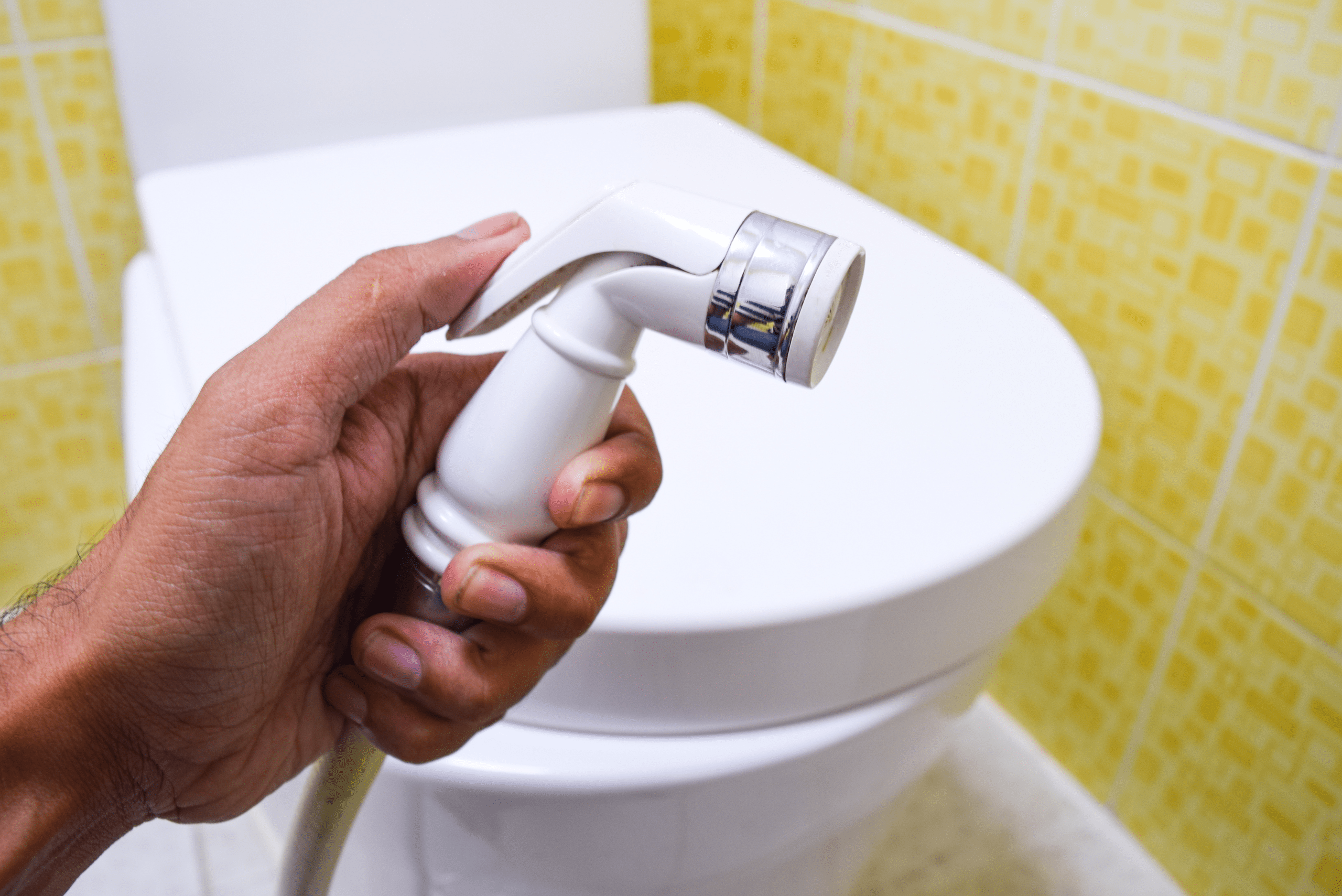 A closeup of someone's hand holding a hose-style bidet.