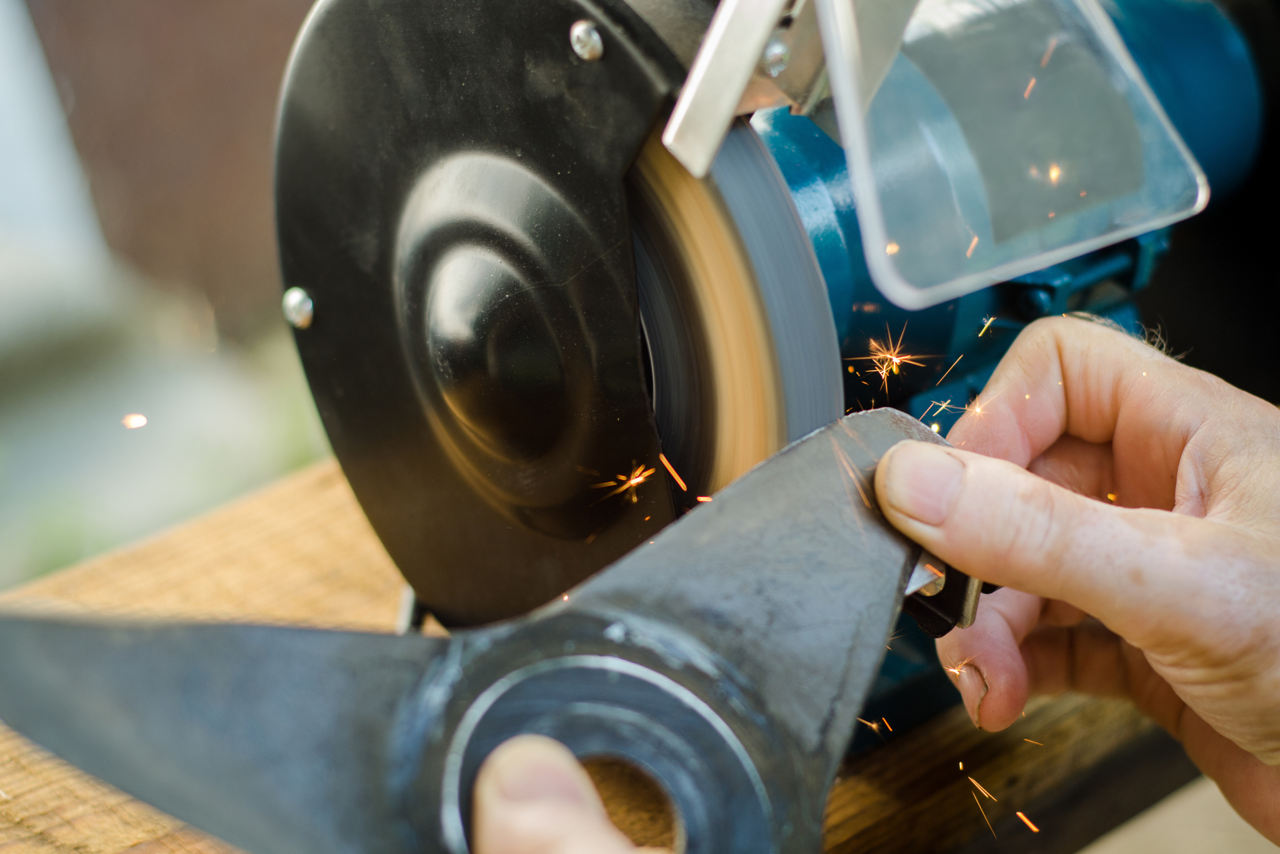 Using a bench grinder to sharpen lawn mower blades.