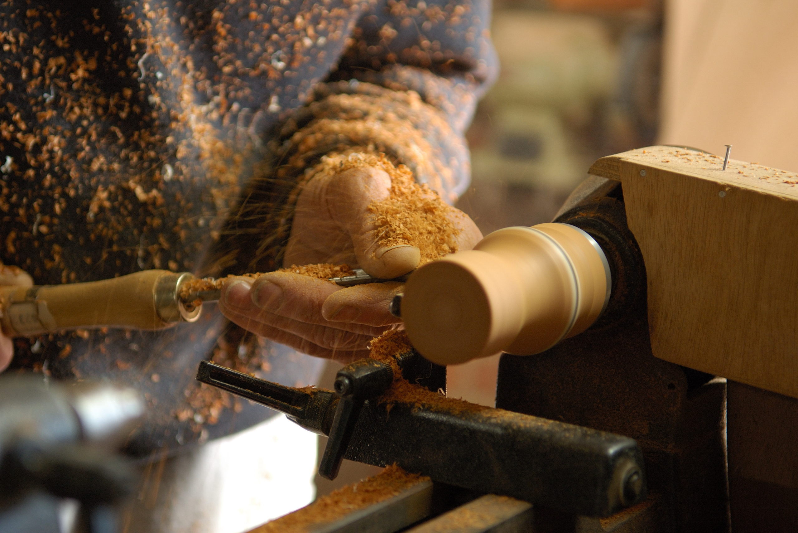 A closeup of someone woodturning a piece of wood.
