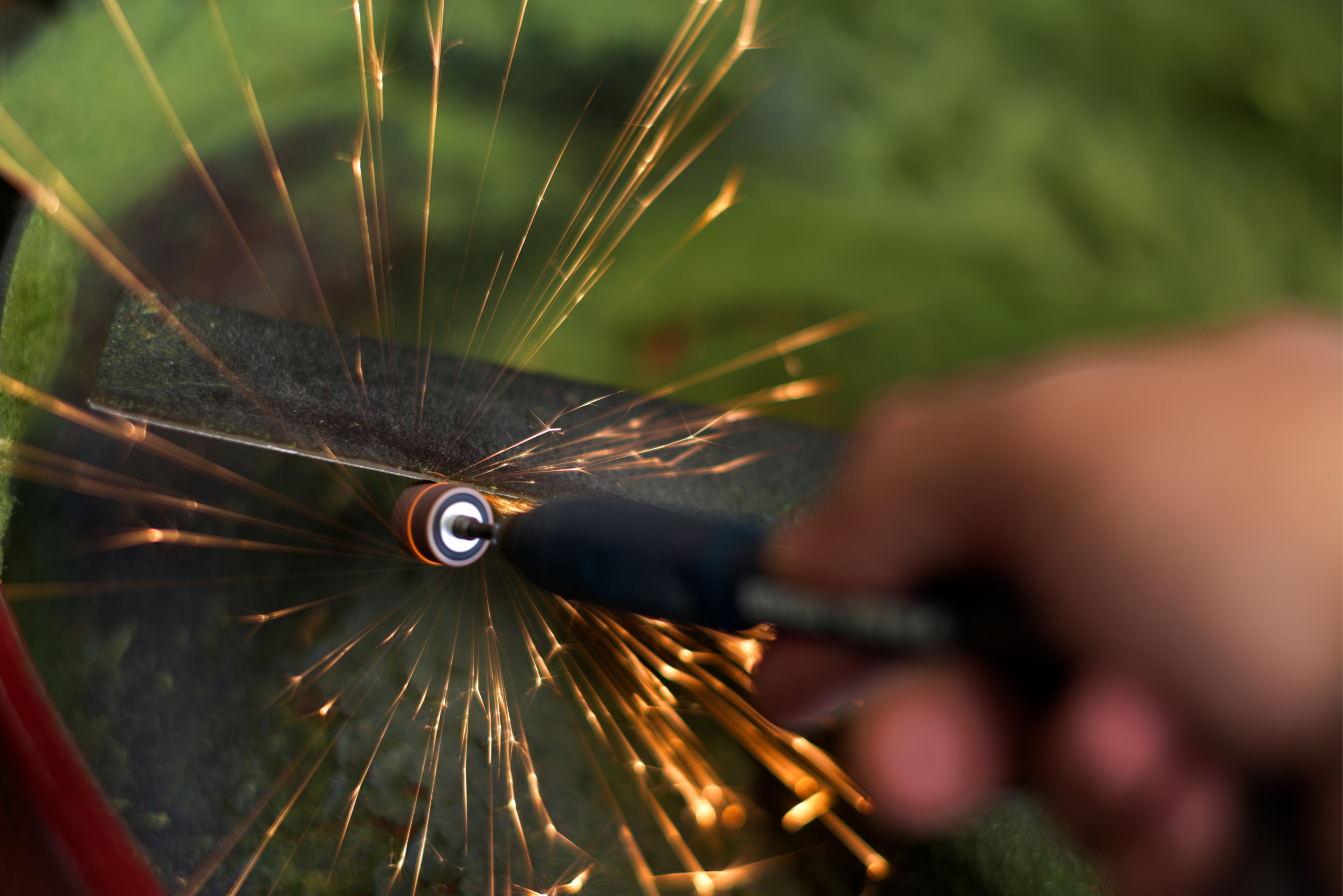 Using a hand grinder to sharpen lawn mower blades.