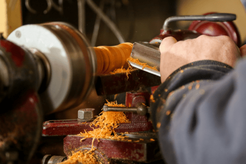 A closeup of someone woodturning a piece of wood.