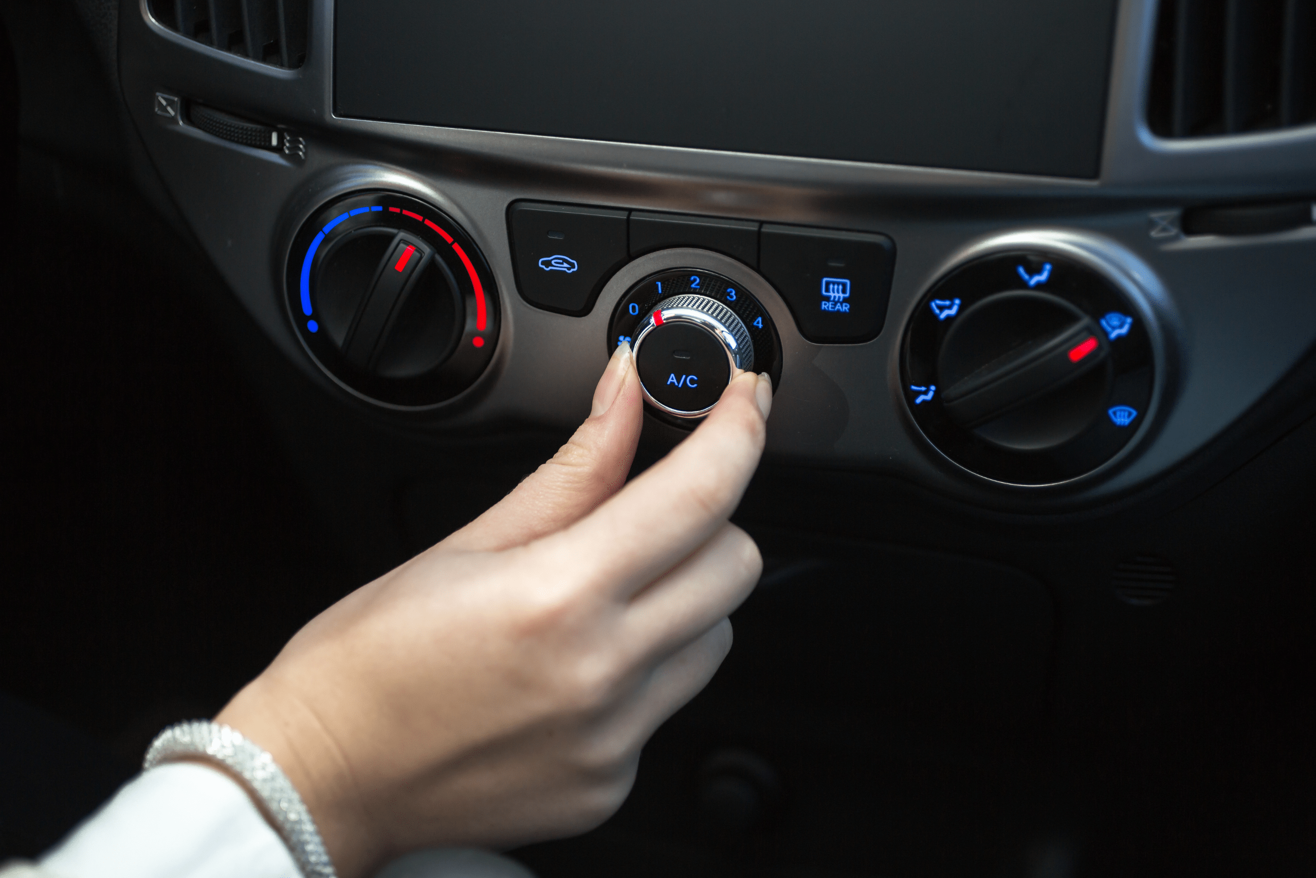 A person adjusting AC fan inside the interior of a car.