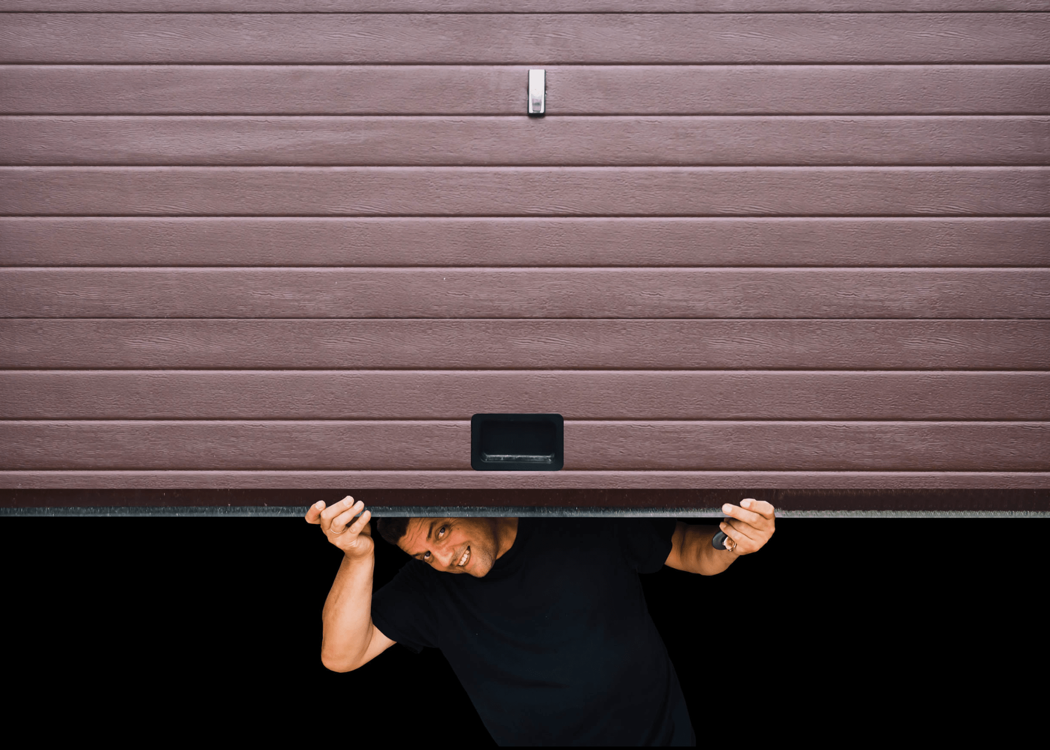 man peeking out from under garage door smiling