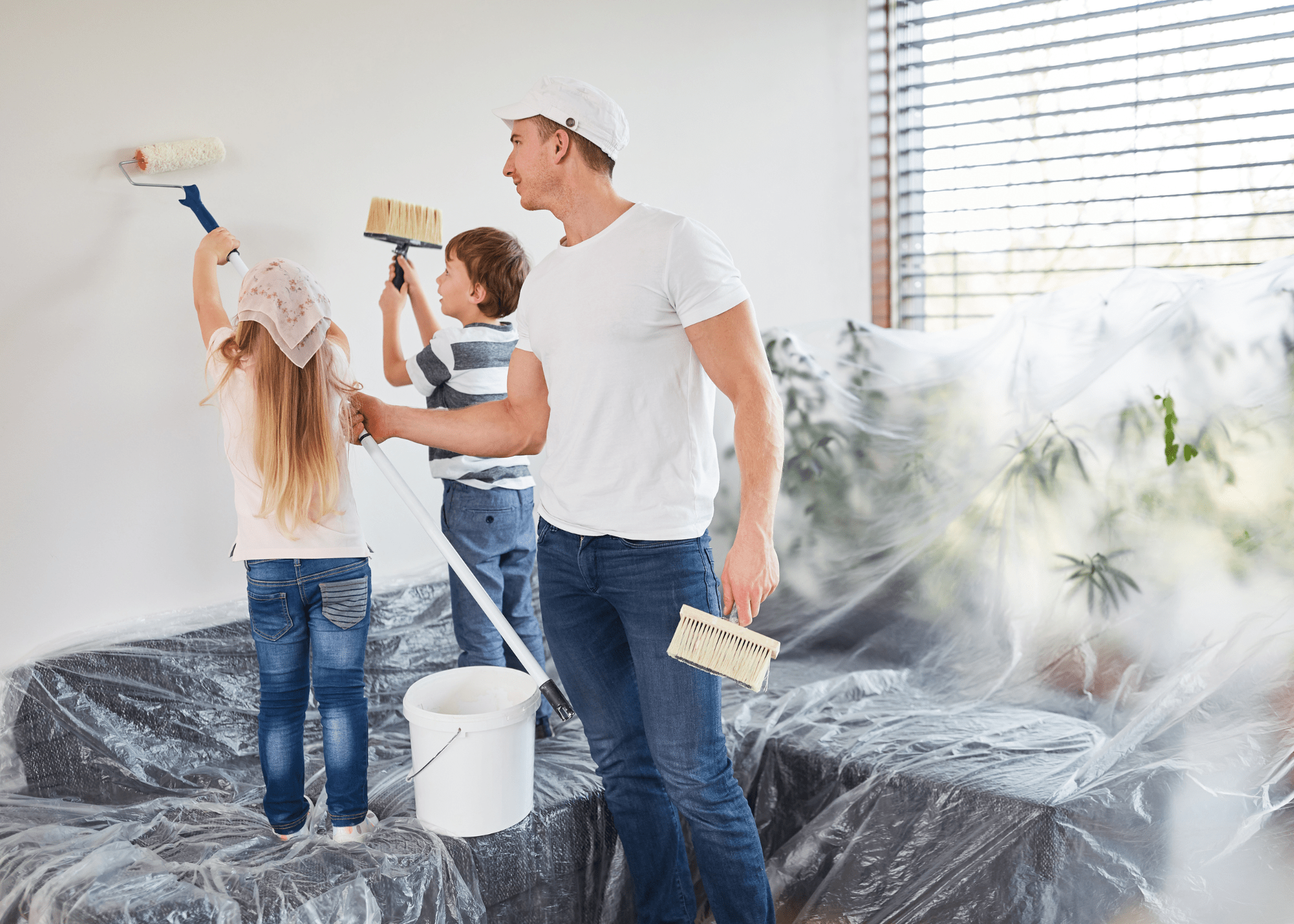 father and children working on painting a wall