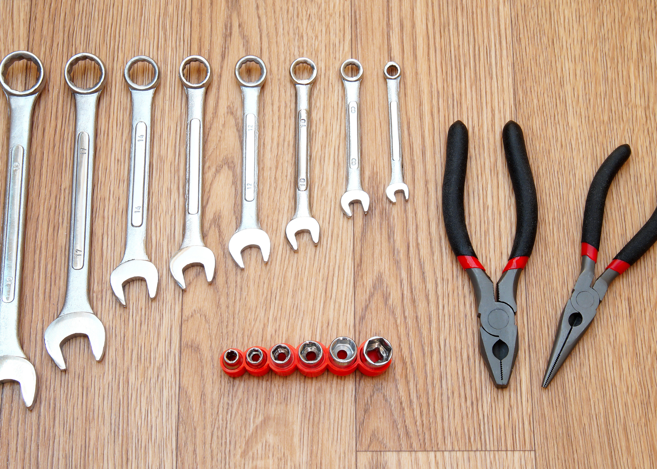 pliers and wrenches on wood background