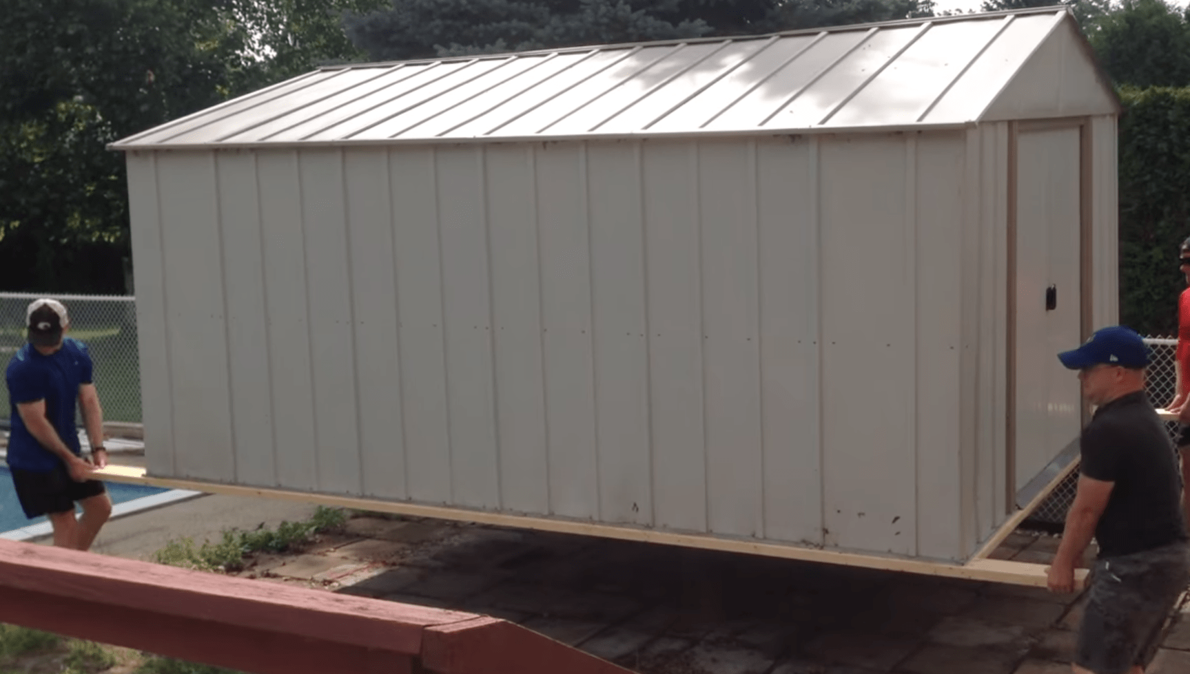 A shed being lifted by 4 people.