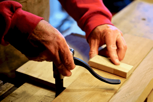 Someone's hands placing a holdfast to secure a piece of wood.