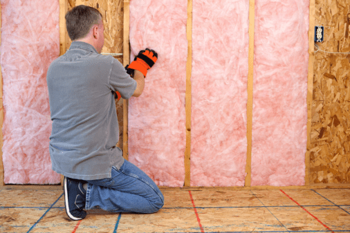A man installing insulation in garage.