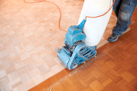 Using a machine to sand wooden floors for restoration.