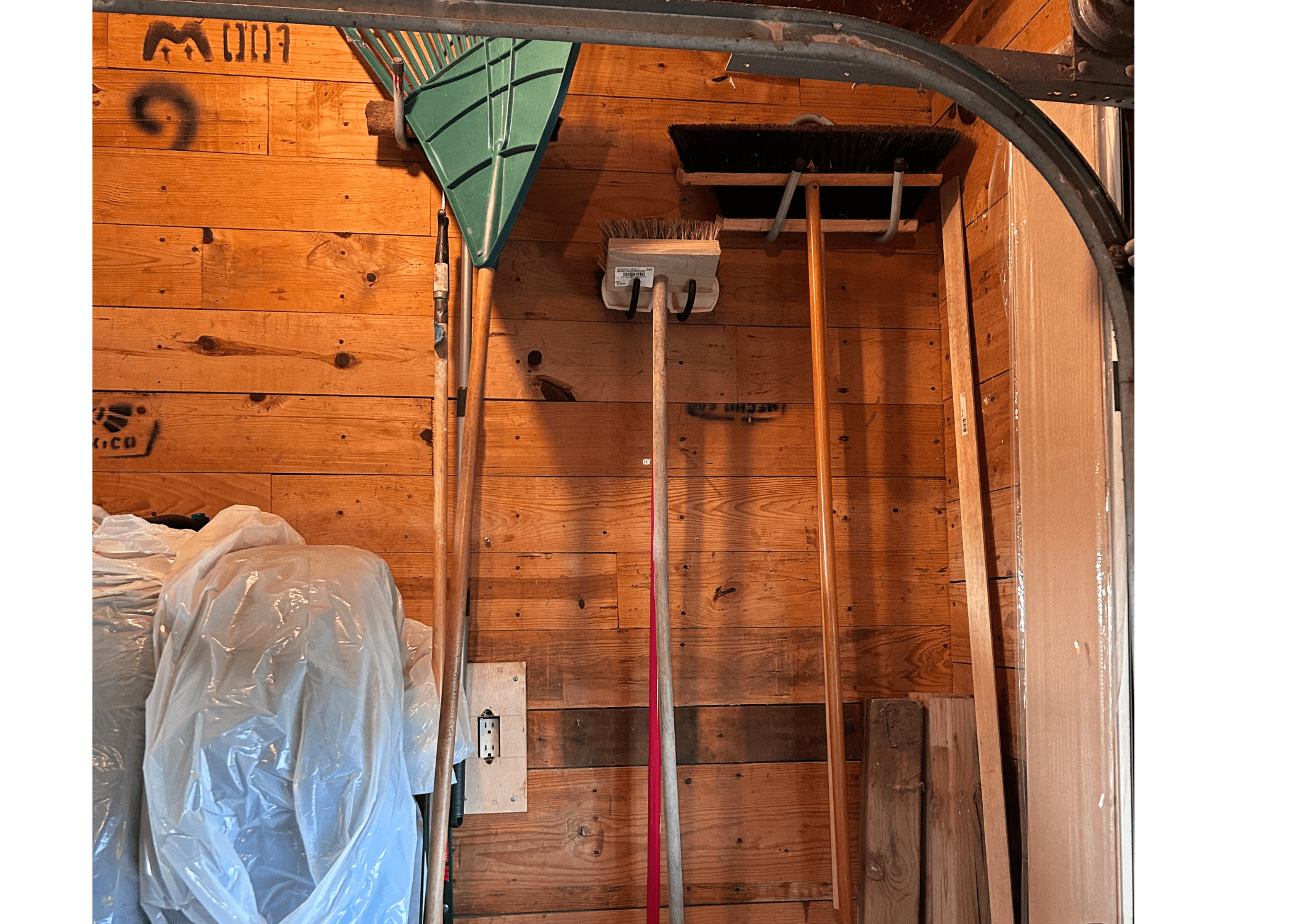 rakes and brooms hanging on wall