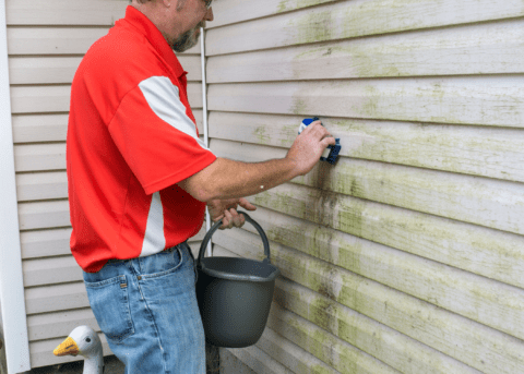 man washing siding with scrub brush