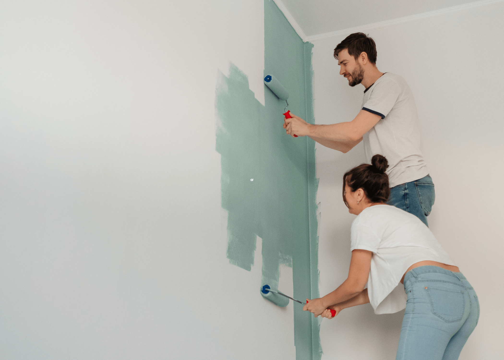 man and woman painting white wall inside house a light teal colour