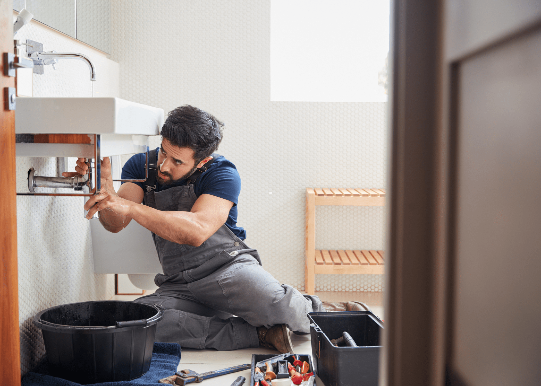 man working under a sink fixing a leaky faucet