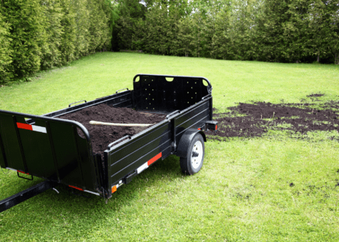 trailer full of soil being dumped on grass