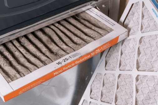 Old furnace filter pulled with new one flanking it.