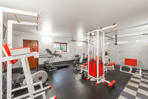 Garage gym with white and red equipment.