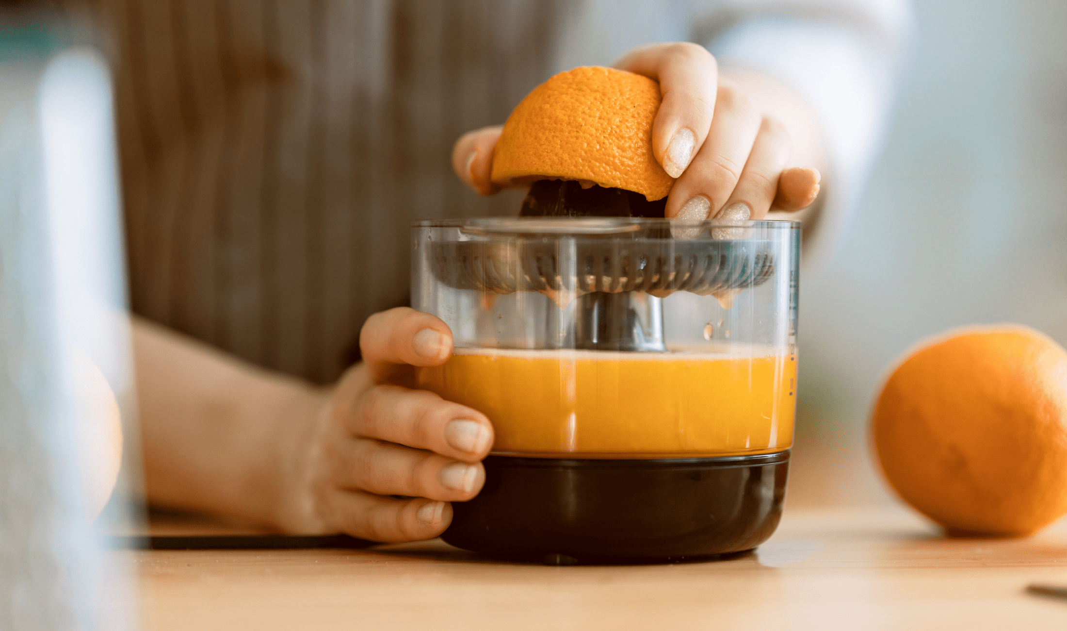 A woman using a simple juicer to juice an orange.