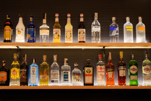 Floating shelf holding liquor bottles.