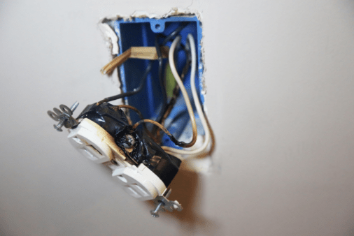 Exposed outlet wiring with burn marks.