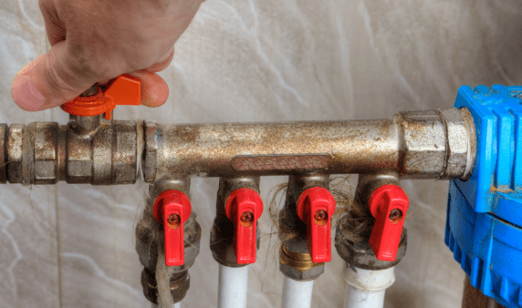 A hand turning a water valve.
