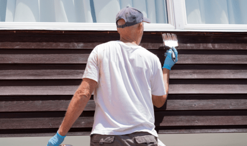 A man painting house siding.