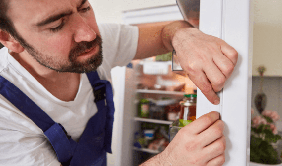 A man inspecting the rubber seal in a fridge.