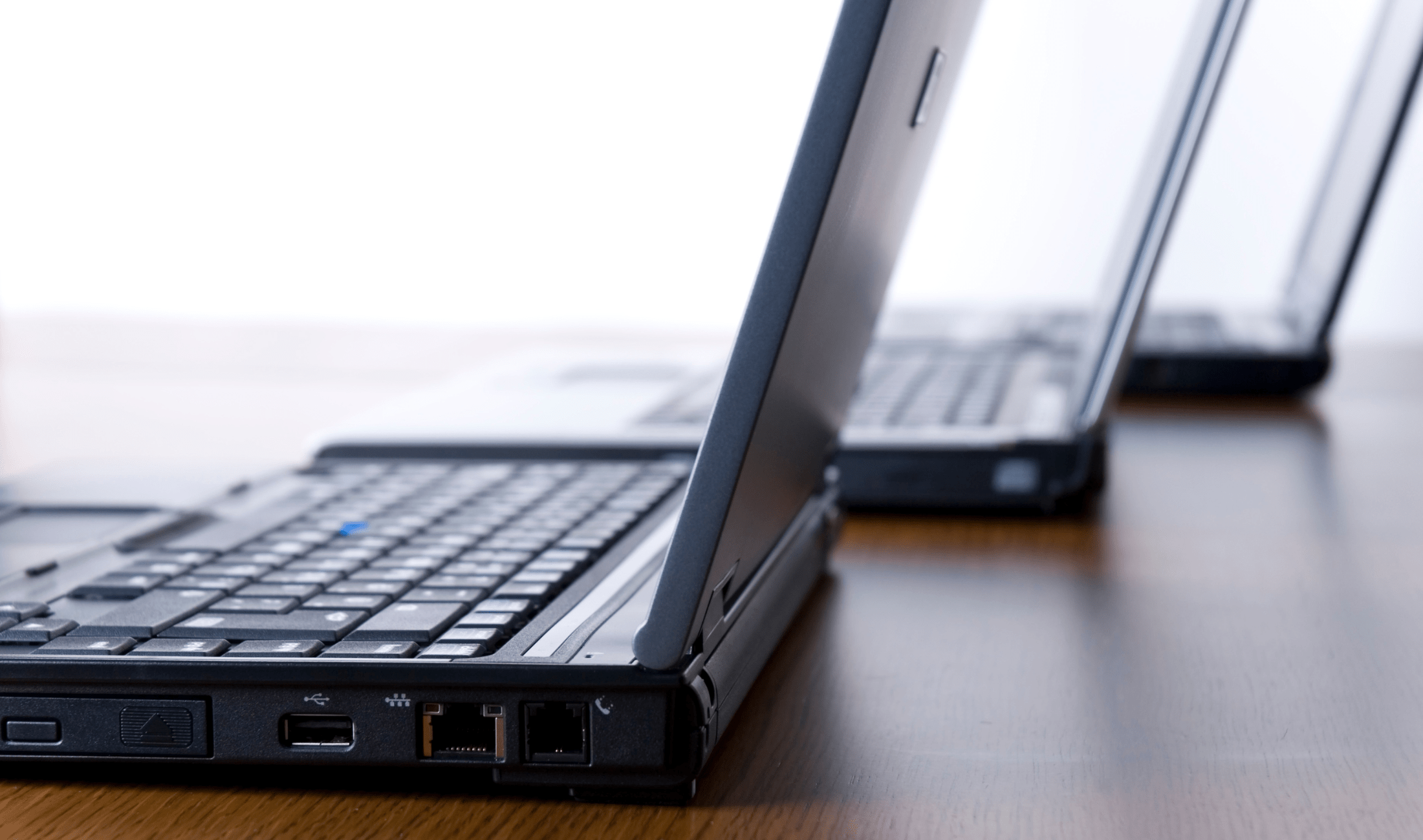 Three older laptops side by side on a table.